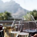 Celebratory toast with glasses of red and white wine against a mountain backdrop, symbolizing awards for advertising excellence