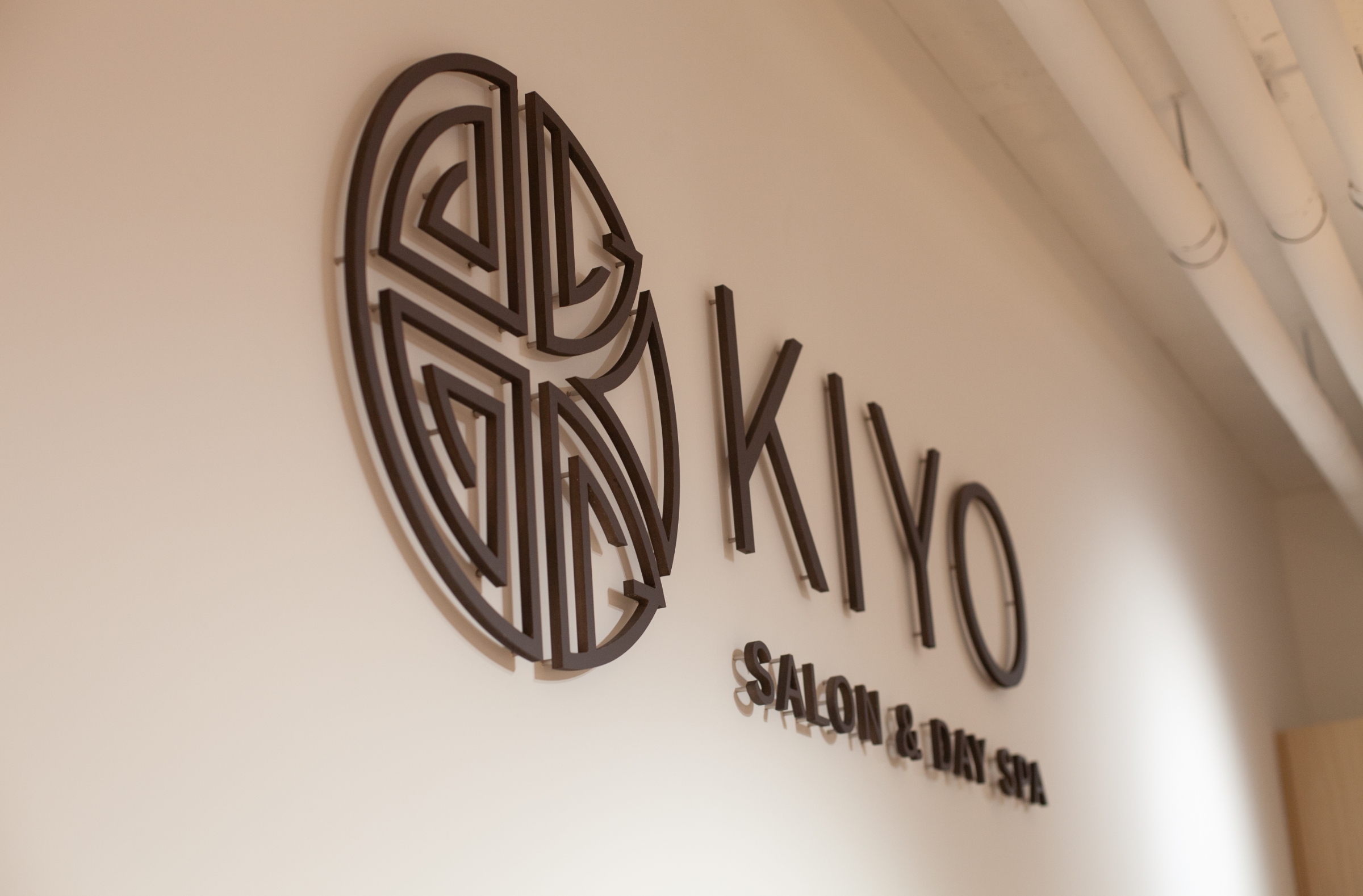 House of Kiyo interior signage. Black minimalist logo pin-mounted on white wall.