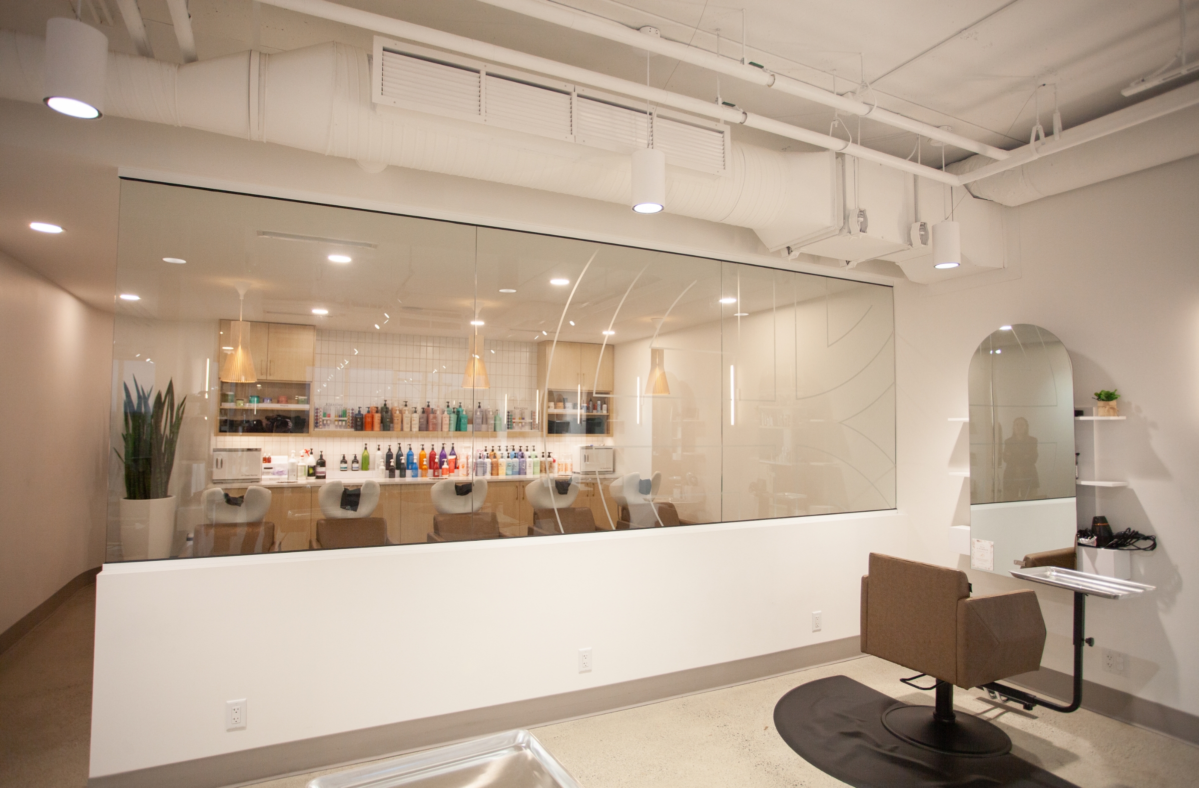 Interior of the salon with salon chairs, arched mirror, and interior window with decal of House of Kiyo logo.