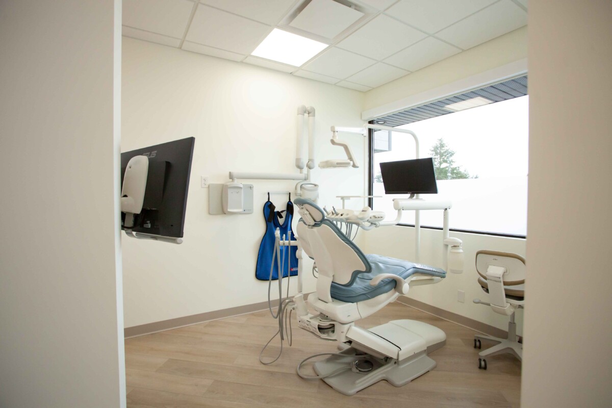 A dental chair with a screen and dental tools in a bright room.