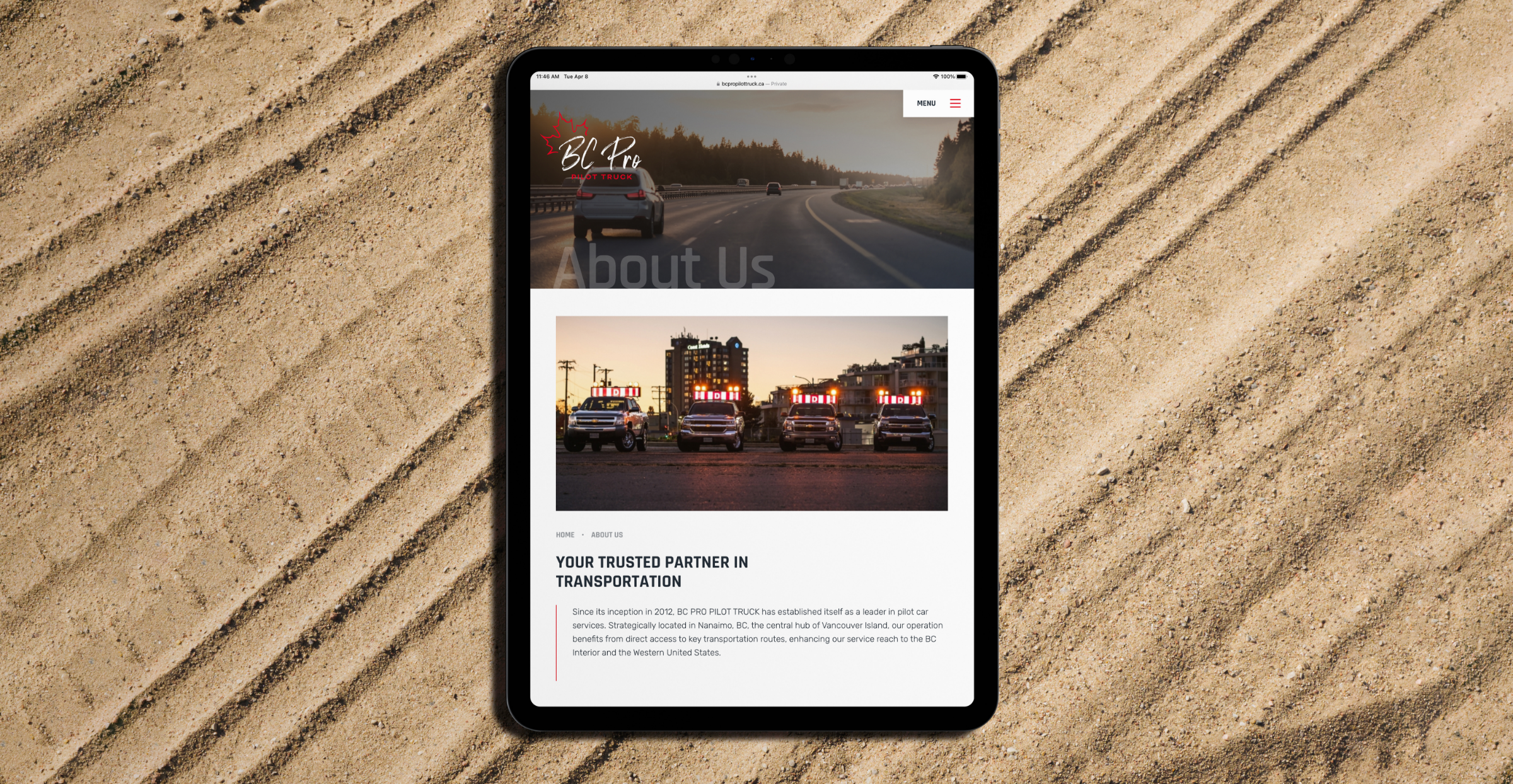 Tablet on a sand road with tire tracks. The tablet is displaying BC PRO PILOT TRUCK's about page, showcasing SEO content strategy by Array.